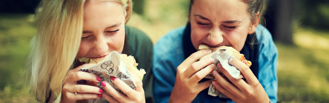 Zwei junge Frauen essen auf einem Fest im Freien.
